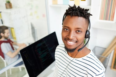 Man on headset with computer behind him